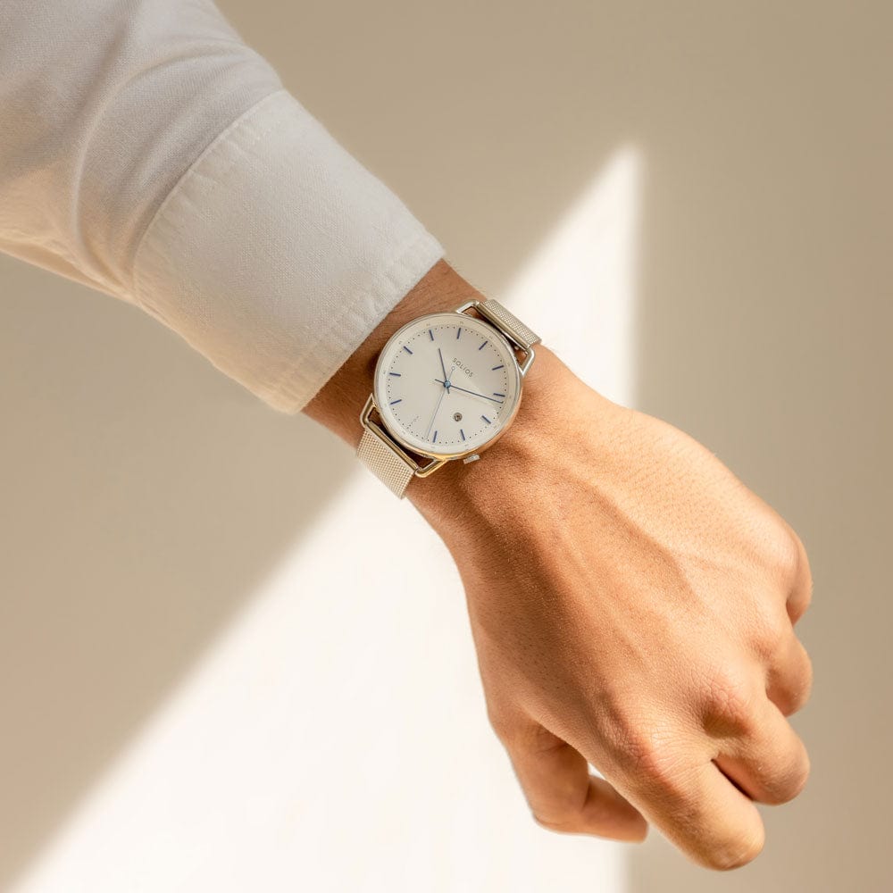 Man wearing the Solios Solar Curve clean white shirt on a white background with defined light, white dial, silver case, silver stainless steel mesh strap