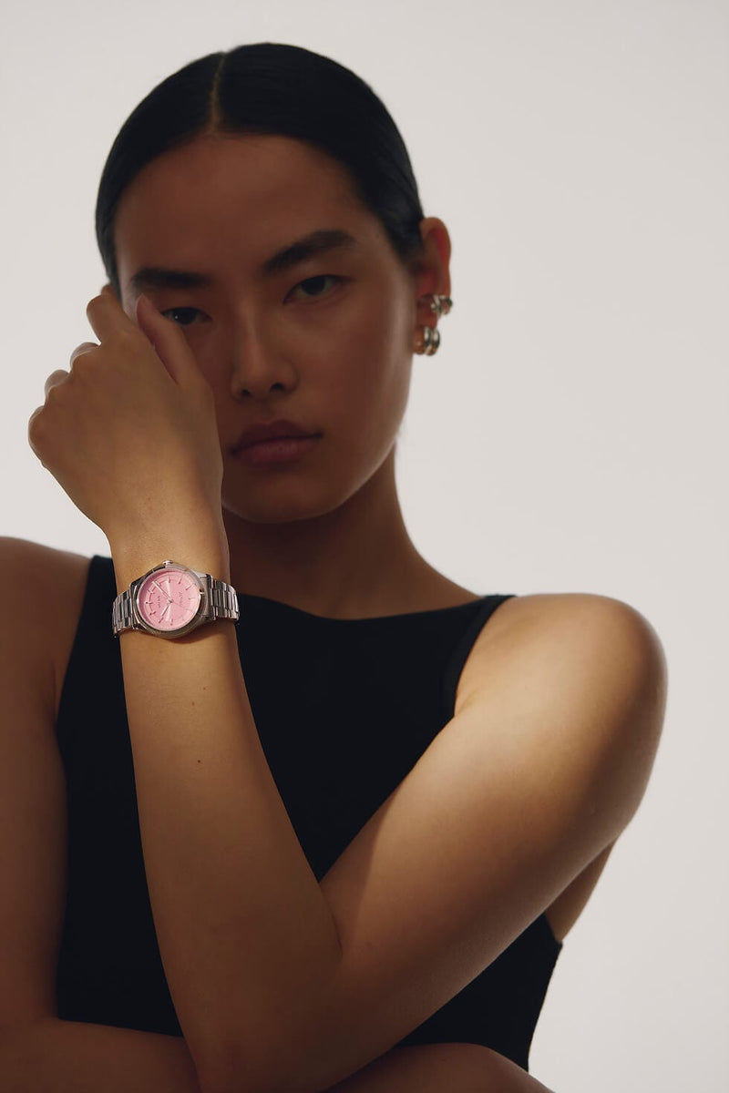 A model wearing a silver-toned metal Sunseeker solar watch with a pink dial and a silver link bracelet, posing against a light gray background.