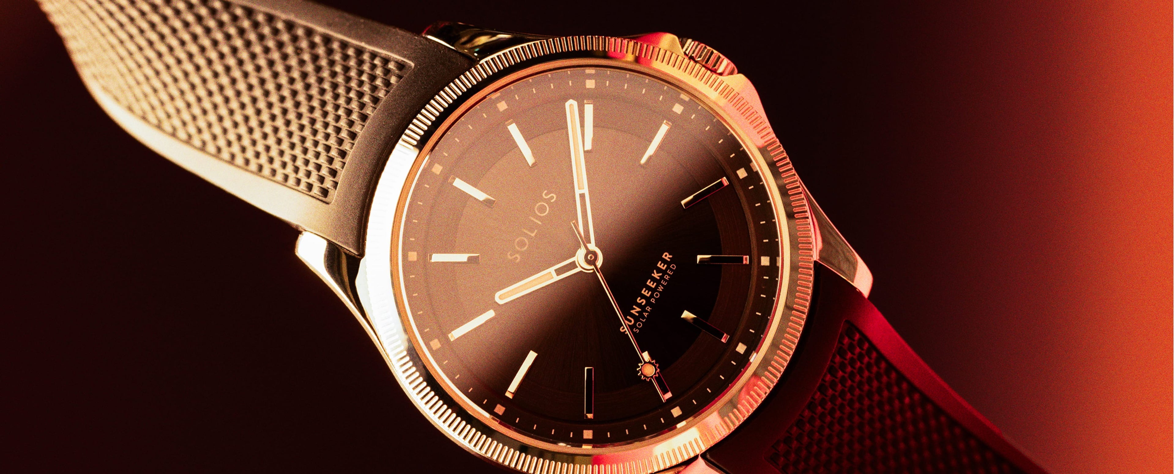Sunseeker Solios solar watch with a black natural rubber strap, twisted on a red and black background