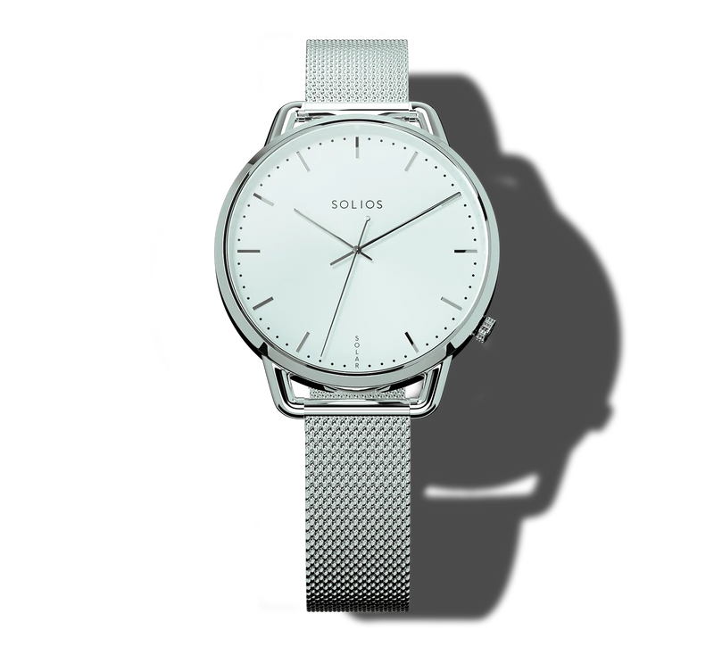 A Solios Curve Mini solar analog watch with a silver-tone stainless steel mesh strap, a round silver bezel, and a white dial with slim silver hands and hour markers, shown against a white background with a soft shadow.