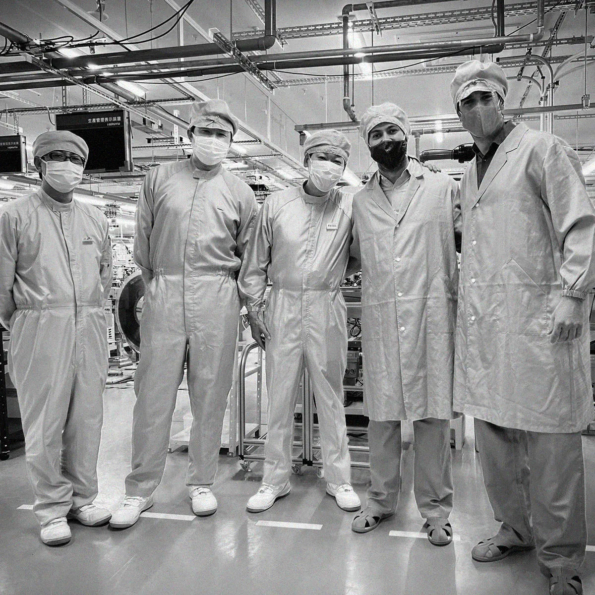 Sam and Alex, Solios cofounders, with the Epson-Seiko team, in cleanroom suits at a solar watch factory in Japan, 2017