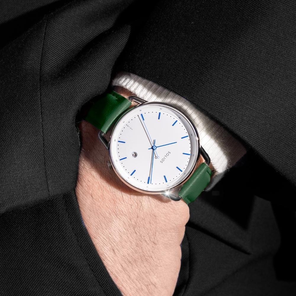 Man wearing the Solios Solar Curve under a navy suit cuff, white dial, silver case, green vegan leather strap