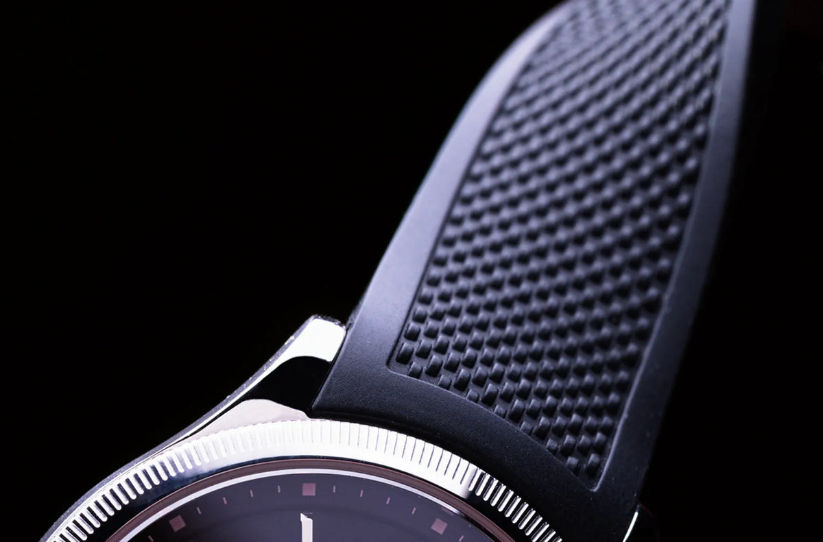 Textured navy Solios natural rubber strap, tapped from rubber trees not petroleum, twisted and sitting on a Sunseeker Solar watch case.