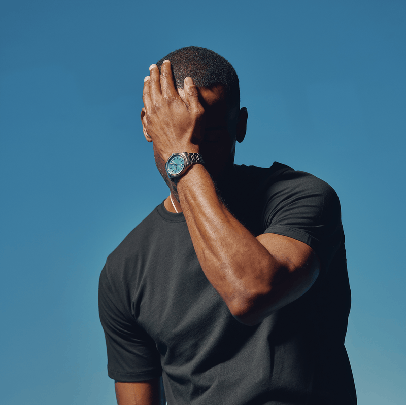 Man wearing a Solios Sunseeker with blue dial and silver case on a blue background