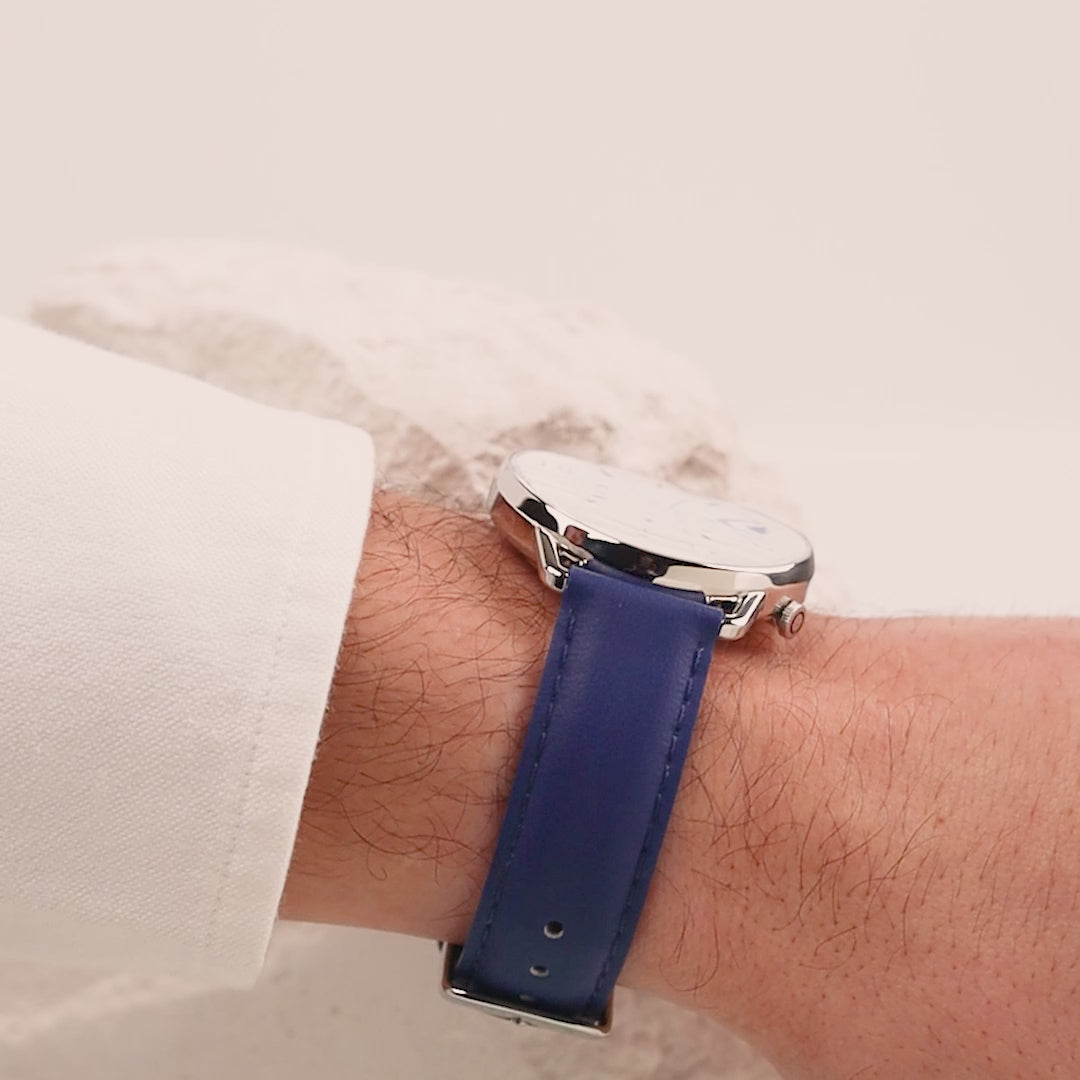Man wearing a white shirt and the Solar Curve, White Dial and Silver case, with the blue vegan leather strap, turning his wrist to show the thin case of the watch and the single sided curve crystal.