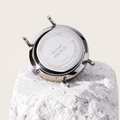 Solios watch caseback resting on a white stone, engraved with a name and date as a custom engraving example